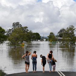 Una familia permanece junto a una calle inundada en Lawrence, a unos 70 kilómetros de la ciudad de Lismore, en Nueva Gales del Sur, Australia. | Foto:SAEED KHAN / AFP