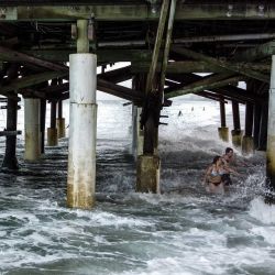 Una pareja camina en el agua bajo el muelle en Cocoa Beach, Florida. | Foto:CHANDAN KHANNA / AFP