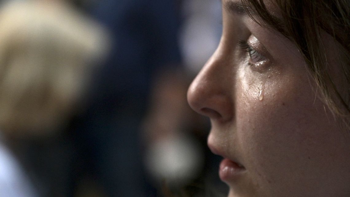 A member of the Ukrainian community in Argentina cries as she sings Ukraine's national anthem during a protest outside of the Russian Embassy in Buenos Aires, on March 1, 2022.