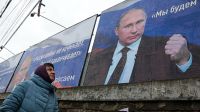 Una mujer pasa en Crimea frente a un cartel de Vladimir Putin. Las protestas contra su invasión a Ucrania se repiten en todo el mundo.