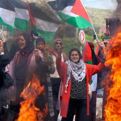 Mujeres palestinas, ondeando banderas nacionales, participan en una protesta contra los asentamientos en los territorios ocupados con motivo del Día Internacional de la Mujer en el pueblo cisjordano de Burqa, al norte de Nablus. | Foto:JAAFAR ASHTIYEH / AFP