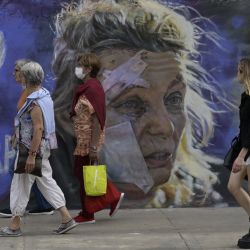 Unas mujeres pasan junto al mural "No a la guerra" del muralista Maximiliano Bagnasco en Buenos Aires. - Bagnasco pinta este mural contra la guerra inspirado en dos imágenes icónicas el retrato de Helena, una maestra de 53 años de edad, de pie fuera de un hospital después del bombardeo de la ciudad oriental de Ucrania de Chuguiv, mientras las fuerzas armadas rusas invaden Ucrania tomada por el fotoperiodista griego de AFP Aris Messinis y Kim Phuc Phan Thi, también conocida como "Napalm Girl", la icónica fotografía de la guerra de Vietnam de 1972 tomada por Nick Ut de AP. | Foto:JUAN MABROMATA / AFP