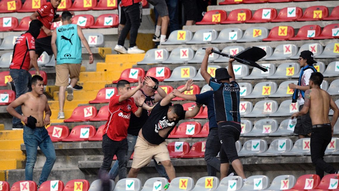 Supporters of Atlas fight with supporters of Queretaro during the Mexican Clausura tournament football match between Queretaro and Atlas at Corregidora stadium in Queretaro, Mexico on March 5, 2022. A match between Mexican football clubs was called off March 5, 2022 after violence by opposing fans spilled onto the field. The game between Queretaro and Atlas at La Corregidora stadium in the city of Queretaro -- the ninth round of the 2022 Clausura football tournament -- was in its 63rd minute when fights between opposing fans broke out.