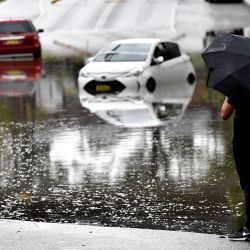 Un residente mira los coches varados en las aguas de la inundación debido a las fuertes lluvias en el suburbio suroeste de Sydney, Australia. | Foto:Muhammad Farooq / AFP