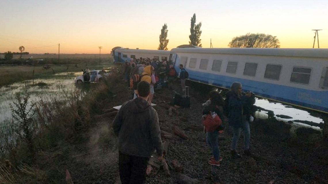 Passengers stand next to a long-distance train that derailed near Olavarría on March 8, 2021. A long-distance train with about 500 passengers on board derailed on Tuesday about 350 km southeast of Buenos Aires, injuring 17 people, officials said.  