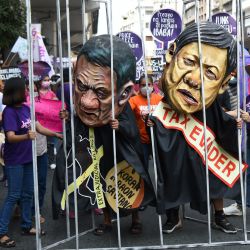 Mujeres activistas sostienen una celda improvisada con colegas que llevan máscaras que representan al presidente Rodrigo Duterte y a Bongbong Marcos, hijo del difunto dictador Ferdinand Marcos, y actual aspirante a la presidencia para las elecciones del 9 de mayo, durante una marcha al Palacio de Malacanang en Manila. | Foto:TED ALJIBE / AFP
