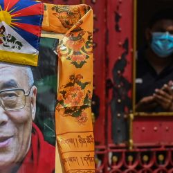 Un guardia de seguridad observa a los partidarios del líder espiritual tibetano Dalai Lama reunidos para observar el 63º aniversario del levantamiento tibetano frente al consulado chino en Calcuta, India. | Foto:DIBYANGSHU SARKAR / AFP