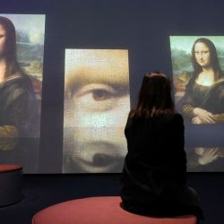 Un visitante observa una pantalla gigante que muestra el retrato de la Mona Lisa de Leonardo Da Vinci antes de la inauguración de la exposición titulada "La Joconde, una exposición inmersiva" en el Palacio de la Bolsa de Marsella, al sur de Francia. | Foto:Nicolas Tucat / AFP