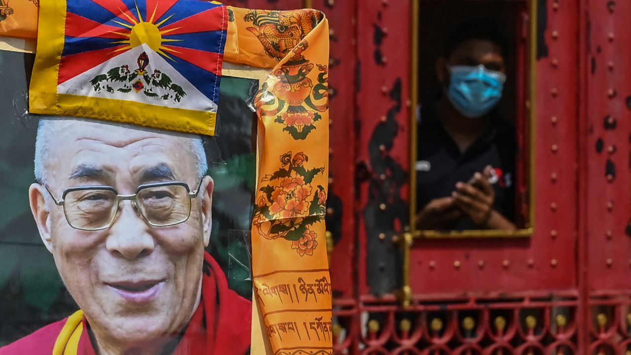 Un guardia de seguridad observa a los partidarios del líder espiritual tibetano Dalai Lama reunidos para observar el 63º aniversario del levantamiento tibetano frente al consulado chino en Calcuta, India. | Foto:DIBYANGSHU SARKAR / AFP