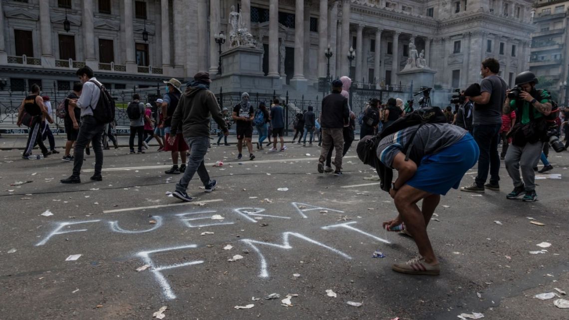 A demonstrator spraypaints in Spanish 'IMF out,' during a protest against the International Monetary Fund (IMF) agreement as lawmakers vote on the bill outside the National Congress building in Buenos Aires, Argentina, on Thursday, March 10, 2022. 
