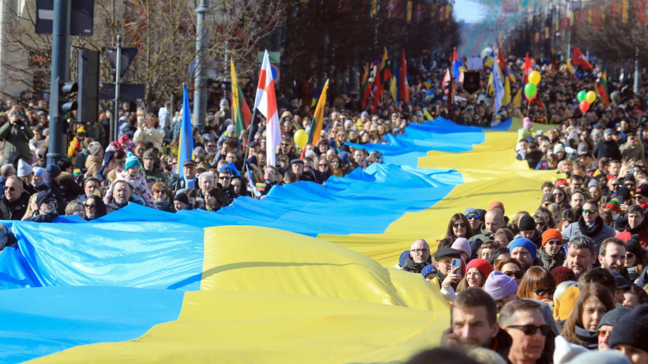 La gente camina con una bandera ucraniana gigante de muchos metros de largo para protestar contra la invasión rusa de Ucrania durante una celebración de la independencia de Lituania en Vilnius, Lituania. | Foto:PETRAS MALUKAS / AFP