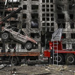 Una grúa retira un coche en ruinas frente a un edificio de apartamentos destruido tras ser bombardeado en el distrito de Obolon, en el noroeste de Kiev, Ucrania. | Foto:ARIS MESSINIS / AFP