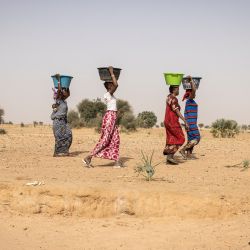 Unas mujeres transportan cubos de agua recogidos en pozos improvisados excavados en el lecho de un río seco en las afueras del pueblo de Madina Torobe, en la región de Matam. - Algunos pastores caminan durante horas para llegar al punto de agua para animales más cercano. El acceso al agua potable en las zonas del noroeste de Senegal es un problema constante.  | Foto:JOHN WESSELS / AFP