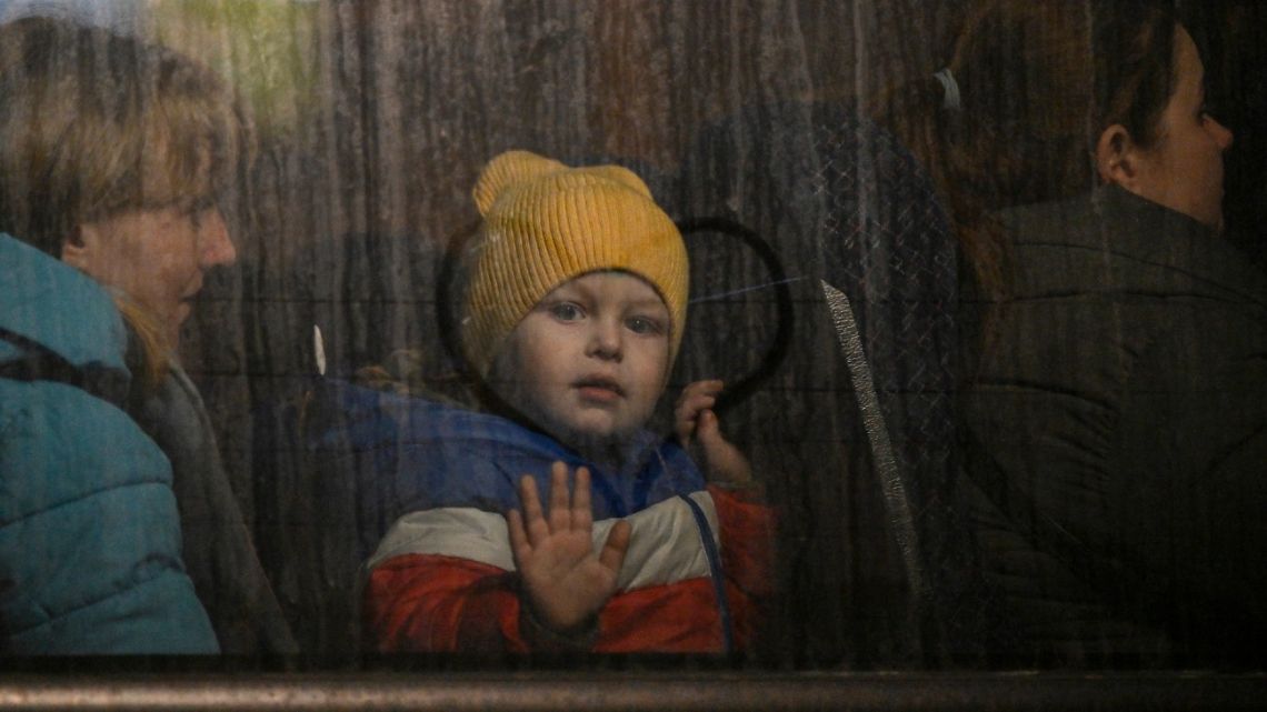 A child greets from the window of a bus after crossing the Ukrainian border with Poland at the Medyka border crossing, southeastern Poland, on March 14, 2022. 