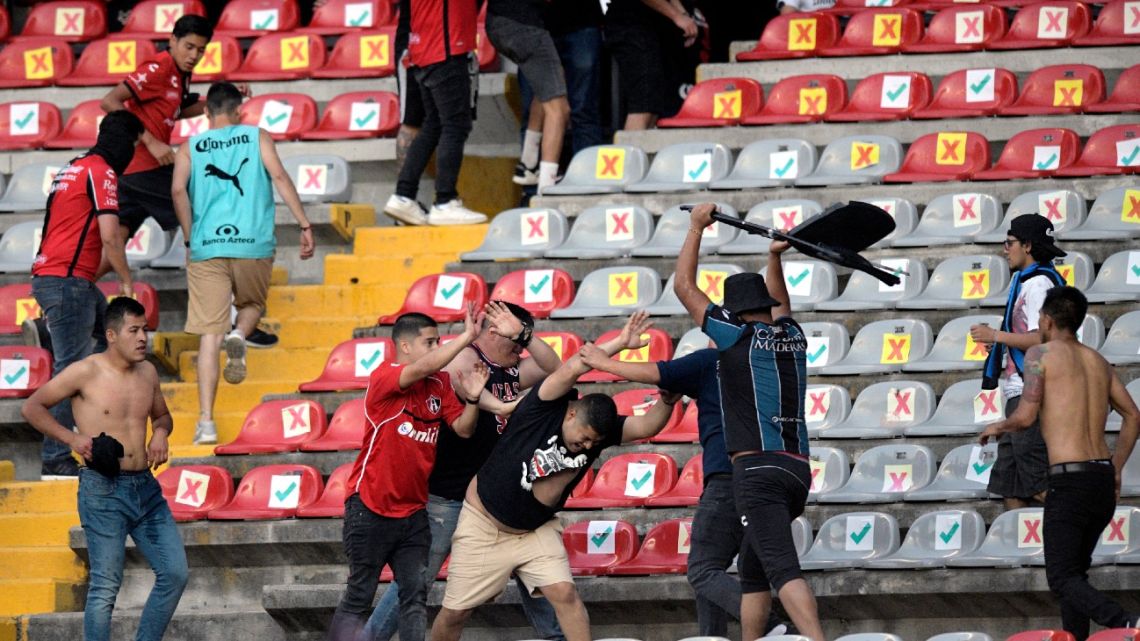 Supporters of Atlas fight with supporters of Queretaro during the Mexican Clausura tournament football match between Queretaro and Atlas at Corregidora stadium in Queretaro, Mexico on March 5, 2022. A match between Mexican football clubs was called off March 5, 2022 after violence by opposing fans spilled onto the field. The game between Queretaro and Atlas at La Corregidora stadium in the city of Queretaro -- the ninth round of the 2022 Clausura football tournament -- was in its 63rd minute when fights between opposing fans broke out. 