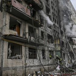 Los bomberos registran un edificio de apartamentos en llamas tras ser bombardeado en el distrito de Obolon, en el noroeste de Kiev, Ucrania. | Foto:ARIS MESSINIS / AFP