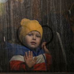 Un niño saluda desde la ventanilla de un autobús tras cruzar la frontera ucraniana con Polonia en el paso fronterizo de Medyka, al sureste de Polonia. - Más de 2,8 millones de refugiados han huido de Ucrania desde que comenzó la invasión, y más de la mitad se dirigieron a Polonia, según la agencia de la ONU para los refugiados. | Foto:LOUISA GOULIAMAKI / AFP
