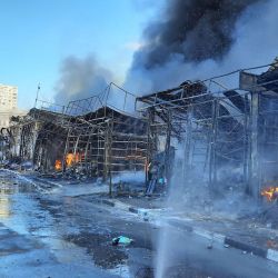 Los bomberos trabajan para extinguir un incendio en un mercado afectado por los bombardeos en Kharkiv, Ucrania. | Foto:Handout / Servicio Estatal de Emergencias de Ucrania / AFP