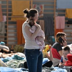 Una mujer sostiene a su bebé de dos meses en un refugio temporal en el gimnasio de un instituto en Przemysl, cerca de la frontera ucraniana-polaca,. - Más de tres millones de personas han huido ya de Ucrania desde que Rusia la invadió el 24 de febrero, según informó Naciones Unidas. | Foto:LOUISA GOULIAMAKI / AFP