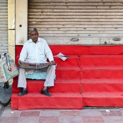 Un hombre lee un periódico frente a una tienda cerrada en Nueva Delhi, India. | Foto:Sajjad Hussain / AFP