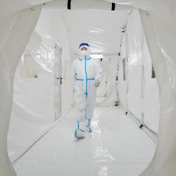 Esta foto muestra a un miembro del personal, con equipo de protección personal (EPP), caminando en el laboratorio Fire Eye, una instalación temporal de pruebas de coronavirus Covid-19, antes de su apertura en Yantai, en la provincia oriental china de Shandong. | Foto:AFP