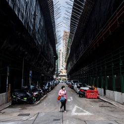Una mujer camina entre viejos edificios residenciales que serán derribados y sustituidos por apartamentos más nuevos como parte del proyecto de renovación urbana del gobierno en Hong Kong. | Foto:ISAAC LAWRENCE / AFP