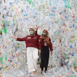 La gente camina a través de una instalación artística hecha con botellas de agua de plástico como parte de una campaña de sensibilización en Indonesia. | Foto:AMAN ROCHMAN / AFP