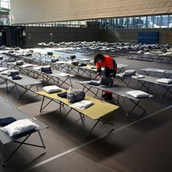 Un ayudante prepara las camas del campamento en un pabellón deportivo en el pequeño pueblo bávaro de Eichenau, cerca de Múnich, en el sur de Alemania. - Aquí se alojan los refugiados de guerra que han tenido que abandonar su país de origen, Ucrania, en los últimos días. | Foto:Christof Stache / AFP