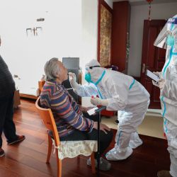 Un trabajador médico toma una muestra de hisopo de una residente que no puede salir convenientemente para ser analizada por el coronavirus COVID-19 en su casa en Shenyang, en la provincia nororiental china de Liaoning. | Foto:AFP