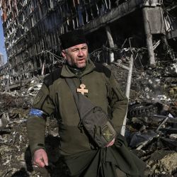 El capellán del ejército ucraniano Mikola Madenski camina entre los escombros fuera del centro comercial Retroville destruido en un distrito residencial, después de un ataque ruso en la capital ucraniana, Kiev. | Foto:ARIS MESSINIS / AFP