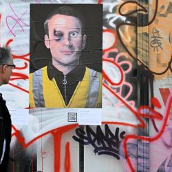 Un hombre pasa junto a un cartel que representa a un magullado presidente francés Emmanuel Macron en París. | Foto:EMMANUEL DUNAND / AFP