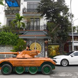 Truong Van Dao pasa frente a una casa en un tanque de madera hecho a partir de la conversión de un viejo minibús en un área residencial en la provincia de Bac Ninh.  | Foto:AFP