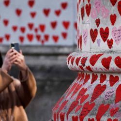 Una mujer toma fotos con un teléfono móvil de los mensajes escribió en el Memorial Covid National Covid, en Londres.  | Foto:AFP