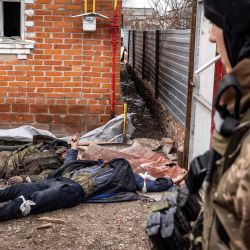 Un soldado ucraniano pasa junto a los cuerpos de los soldados rusos que yacían en el suelo después de que las tropas ucranianas recuperaron la aldea de Mala Rogan, al este de Kharkiv.  | Foto:AFP