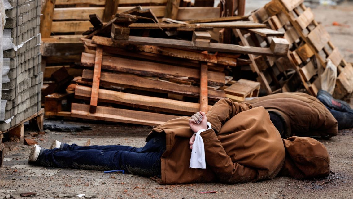 The body of a man, with his wrists tied behind his back, lies on a street in Bucha, just northwest of the capital Kyiv on April 2, 2022. The bodies of at least 20 men in civilian clothes were found lying in a single street on April 2, 2022, after Ukrainian forces retook the town of Bucha near Kyiv from Russian troops, AFP journalists said. 