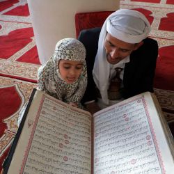 Un hombre musulmán escucha cómo un niño lee el Corán, el libro sagrado del Islam, en la Gran Mezquita de la capital de Yemen, Saná, el primer día del mes sagrado del Ramadán. | Foto:MOHAMMED HUWAIS / AFP