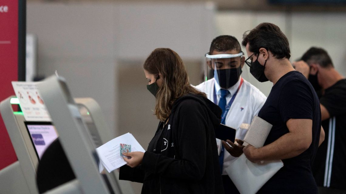 In this AFP file photo taken on April 13, 2021, travellers are assisted by an airport employee in Galeão International Airport in Rio de Janeiro, Brazil. Brazil loosened its pandemic restrictions for international travellers as of April 2, 2022. 