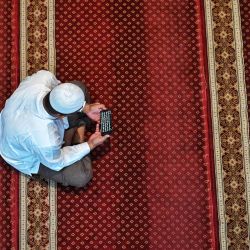 Un hombre lee una copia digital del Corán en su teléfono en la mezquita Al Makmur durante el mes sagrado del Ramadán en Banda Aceh, Indonesia. | Foto:CHAIDEER MAHYUDDIN / AFP
