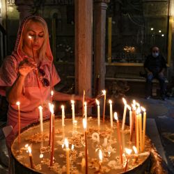 Una mujer enciende una vela en la Iglesia del Santo Sepulcro en la Ciudad Vieja de Jerusalén. | Foto:Menahem Kahana / AFP