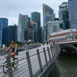 Una persona circula en bicicleta a través de un puente junto al distrito financiero de negocios en Singapur. | Foto:ROSLAN RAHMAN / AFP