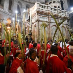 El clero católico romano lleva ramas de palma mientras rodea el edículo durante la procesión del Domingo de Ramos en la Iglesia del Santo Sepulcro en la Ciudad Vieja de Jerusalén. | Foto:AHMAD GHARABLI / AFP