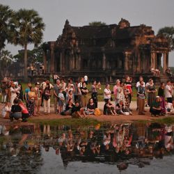 Los turistas se reúnen para ver la salida del sol sobre el complejo de templos de Angkor Wat, Patrimonio de la Humanidad de la UNESCO, en la provincia de Siem Reap, Camboya. | Foto:TANG CHHIN SOTHY / AFP