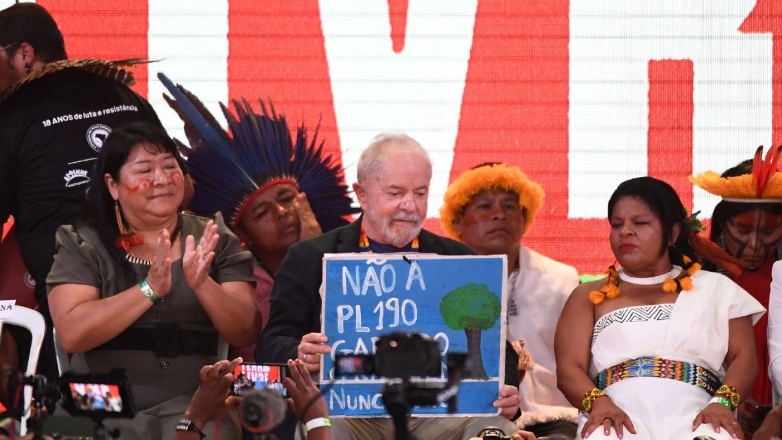Luiz Inacio Lula da Silva holds a poster against a bill allowing mining in indigenous lands at Terra Livre Indigenous Camp in Brasília, on April 12, 2022.