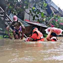 Esta foto muestra al personal de la guardia costera evacuando a los residentes locales de sus casas inundadas en la ciudad de Panitan, provincia de Capiz, cuando las fuertes lluvias provocadas por la tormenta tropical Megi inundaron la zona. | Foto:Handout / Philippine Coast Guard (PCG) / AFP