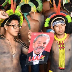 Indígenas brasileños sostienen un cartel con la imagen del ex presidente brasileño (2003-2011) y candidato presidencial Luiz Inacio Lula da Silva durante su visita al campamento indígena Terra Livre en Brasilia. | Foto:EVARISTO SA / AFP