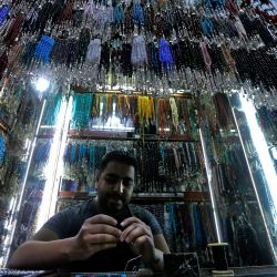 Un vendedor arma una cuenta de oración mientras otras cuelgan sobre él en una tienda del mercado de al-Hamidiya en Damasco, capital de Siria, durante el mes sagrado musulmán del Ramadán. | Foto:LOUAI BESHARA / AFP