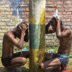 Los trabajadores se bañan bajo los grifos en una calle de las afueras de Amritsar, India. | Foto:NARINDER NANU / AFP