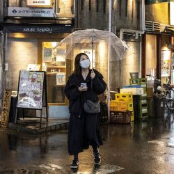 Una mujer camina por una calle mientras llueve por la tarde en Tokio. | Foto:CHARLY TRIBALLEAU / AFP