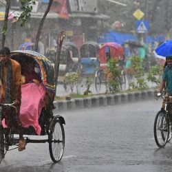 Tiradores de rickshaw se abren paso por una calle bajo una fuerte lluvia en Dhaka, Bangladesh. | Foto:MUNIR UZ ZAMAN / AFP