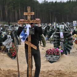 Un trabajador comunal coloca una cruz en una tumba durante un funeral en un cementerio en Irpin, donde hay al menos tres filas de tumbas nuevas para los muertos durante la invasión rusa de Ucrania. | Foto:SERGEI SUPINSKY / AFP